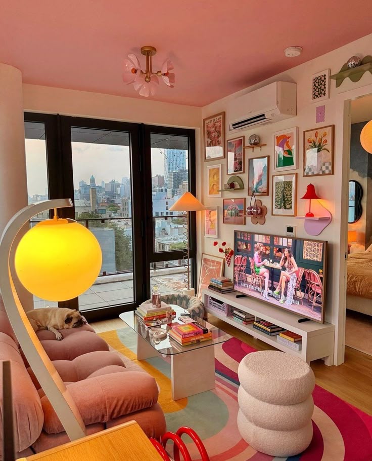 Cozy living room with colorful decor, gallery wall art, modern furniture, and a city view window. Pug relaxing on a pink sofa.