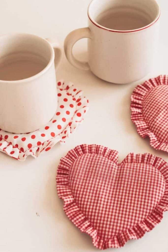 Two ceramic mugs on polka dot coasters accompanied by heart-shaped gingham fabric pads.