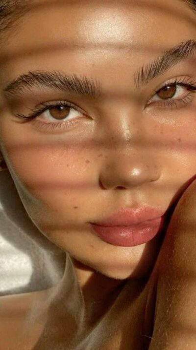 4d474101-97f0-461d-9d1c-00af1da4fb59 - Handy Home Close-up of a woman's face with soft sunlight and shadow patterns, showcasing her natural beauty and captivating eyes.