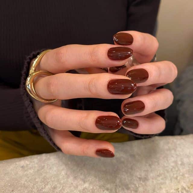 5d12fa5a-20fb-409e-b2e3-904825246ecf - Handy Home Elegant hands with glossy burgundy nail polish, showcasing gold rings against a neutral background. Perfect for nail art inspiration.