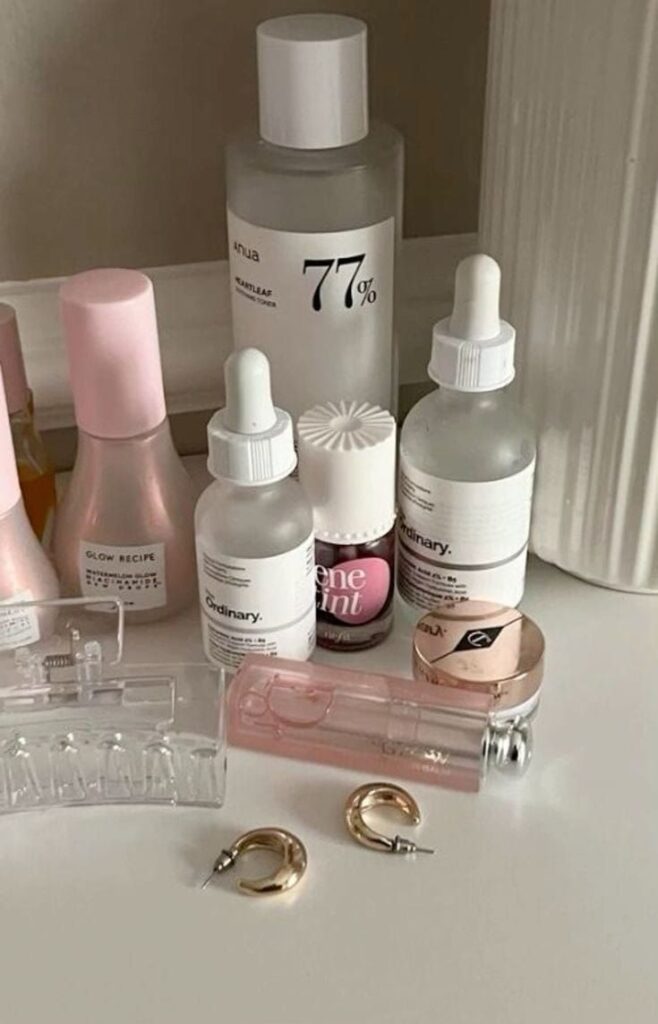 Aesthetic skincare and makeup collection with serums and golden hoop earrings on a vanity table. Perfect for beauty enthusiasts.