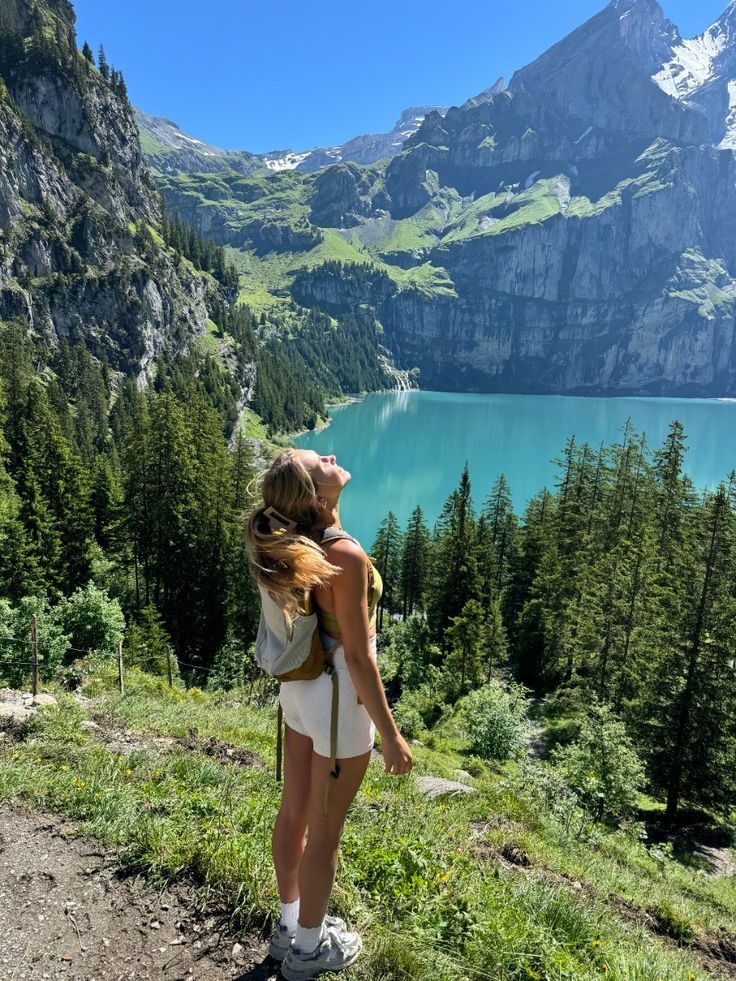 Woman enjoying scenic view of turquoise lake and mountains, Kandersteg, Switzerland. Summer hiking adventure in nature.