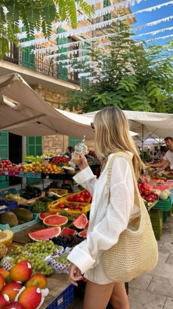 Woman shopping at vibrant outdoor market with fresh fruits and colorful decor. Summer vibe, healthy lifestyle concept.