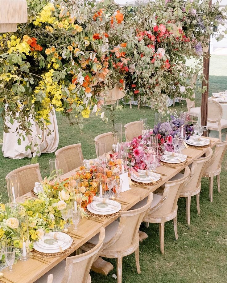 Elegant outdoor table setting adorned with colorful hanging and table florals, perfect for a garden wedding or event.