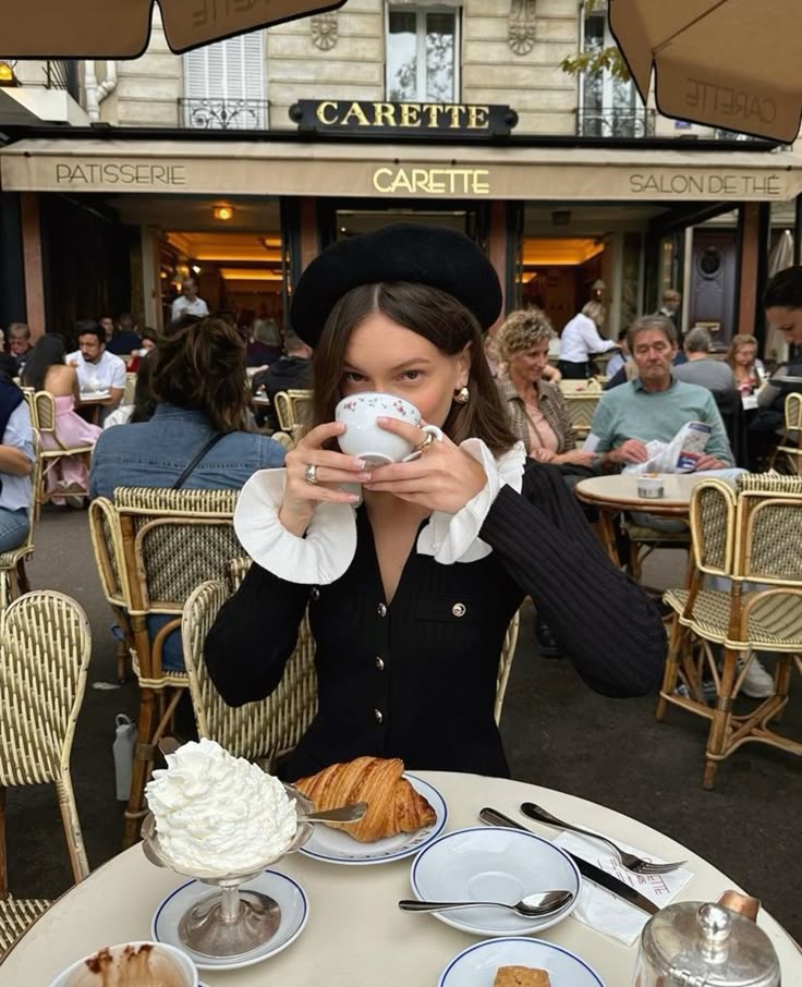 Woman enjoying coffee at Parisian cafe with pastries on table, wearing a beret. Charming outdoor dining scene.
