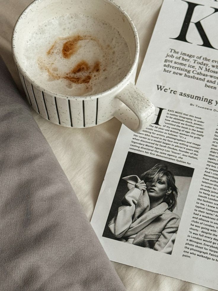 Cozy morning scene with a latte in a speckled mug next to a magazine featuring a stylish black-and-white photo.