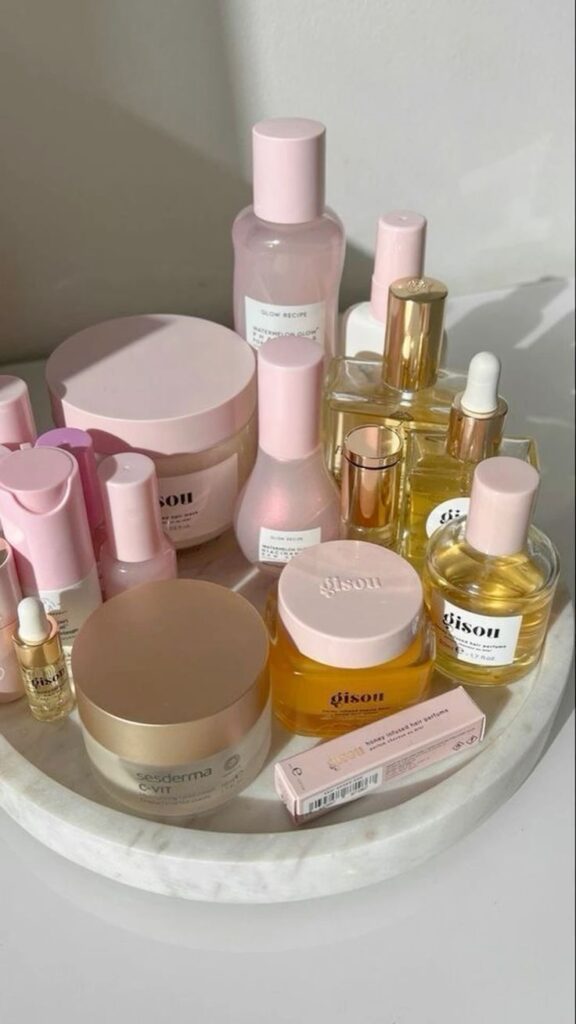 Assorted skincare products on a marble tray, featuring pink and gold packaging, creating a luxurious beauty display.