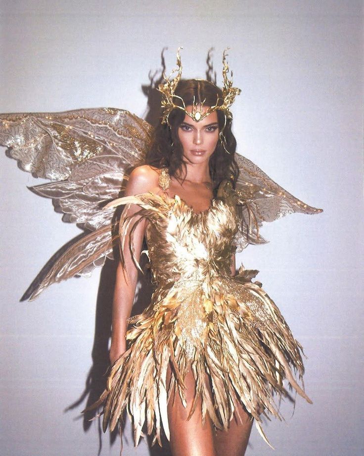 Elegant woman in a gold feathered dress with intricate wings and a delicate crown, embodying a mythical fairy-like appearance.