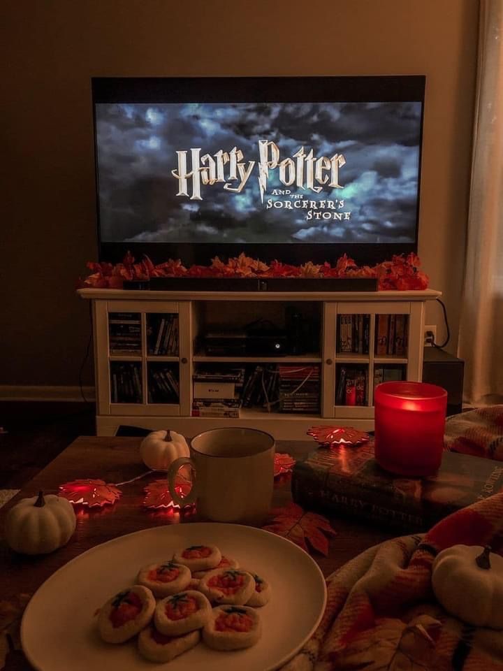 Cozy fall night with Harry Potter on TV, cookies, candles, and pumpkins creating a warm autumn ambiance in front of the living room setup.
