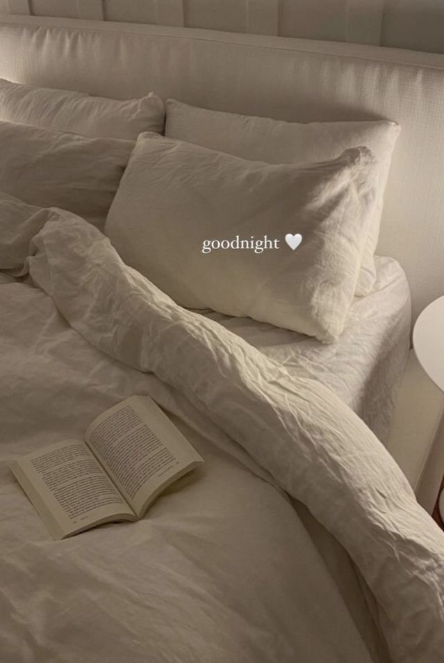 Cozy bedroom setting with an open book on bed; pillows say goodnight with a heart. Perfect for relaxation and reading vibes.