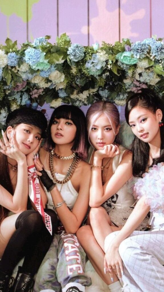 Four stylish women pose under a flower arch, exuding elegance and confidence in trendy outfits.