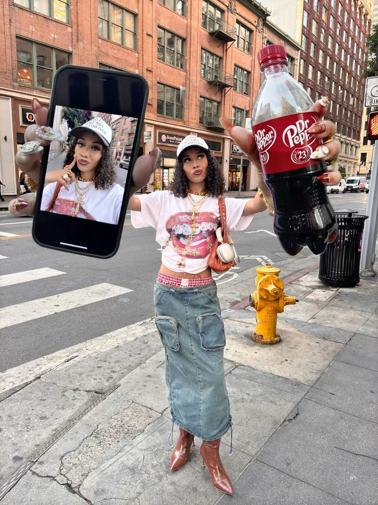 Fashionable woman poses with a phone and Dr. Pepper in a city street, wearing a trendy outfit, denim skirt, and hat.