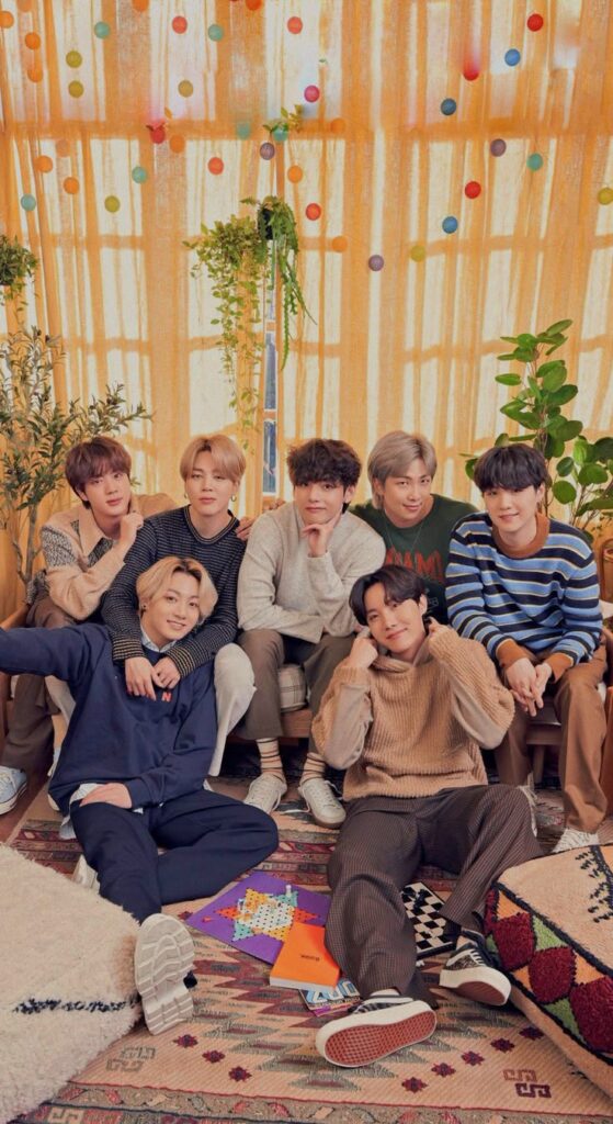 Seven people sitting together in a cozy, colorful room with plants and decorations.