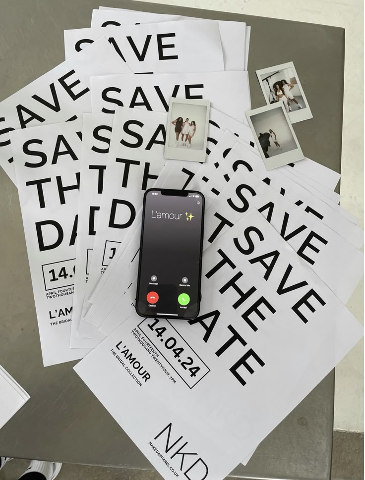 Save the Date invitations on a table with a phone call from L'amour visible; wedding or event preparation theme.