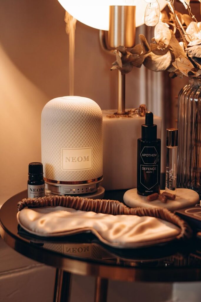 Aromatherapy setup with diffuser, essential oils, an eye mask, and relaxing decor on a stylish bedside table.