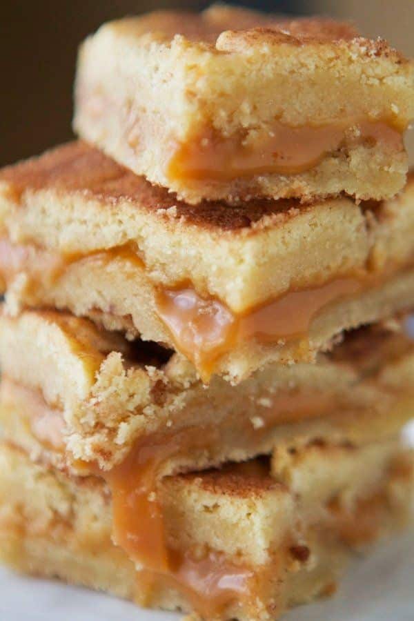 Stack of gooey caramel blondies with golden crust and luscious filling, perfect dessert for any sweet tooth craving.