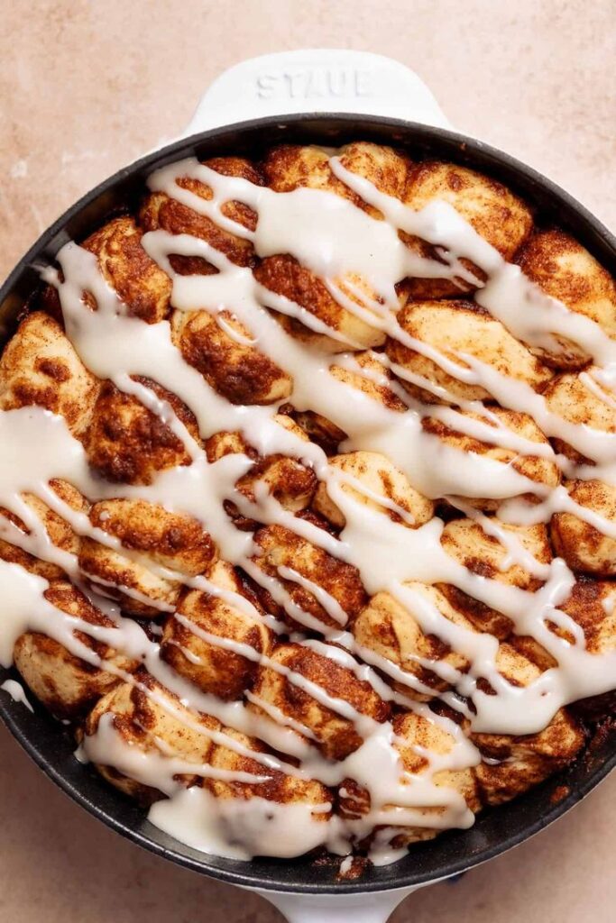 Cinnamon rolls drizzled with creamy icing in a skillet, perfect for a sweet breakfast or dessert treat. Delicious and inviting!