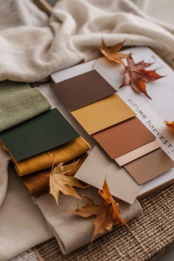 Autumn color palette with fabric swatches and leaves, featuring warm, earthy tones for seasonal design inspiration.