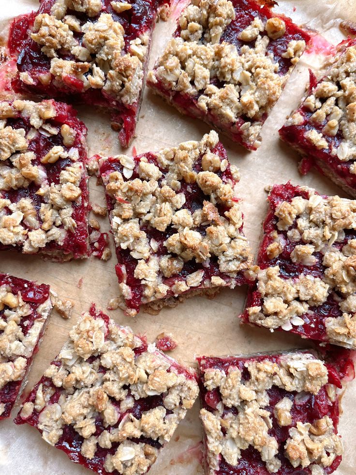 Delicious homemade berry crumble bars topped with golden oat crust on parchment paper, perfect for a sweet snack or dessert.