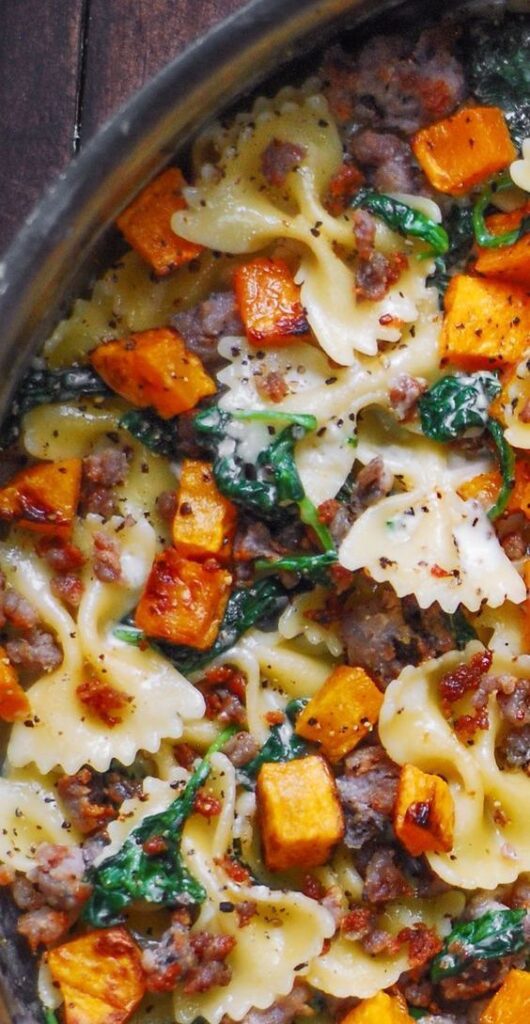 Bowtie pasta with roasted butternut squash, spinach, and sausage in a creamy sauce. Perfect for a hearty autumn meal.