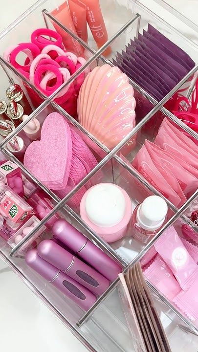 Organized makeup drawer with pink and purple accessories and beauty products, including brushes, lipsticks, and skincare items.