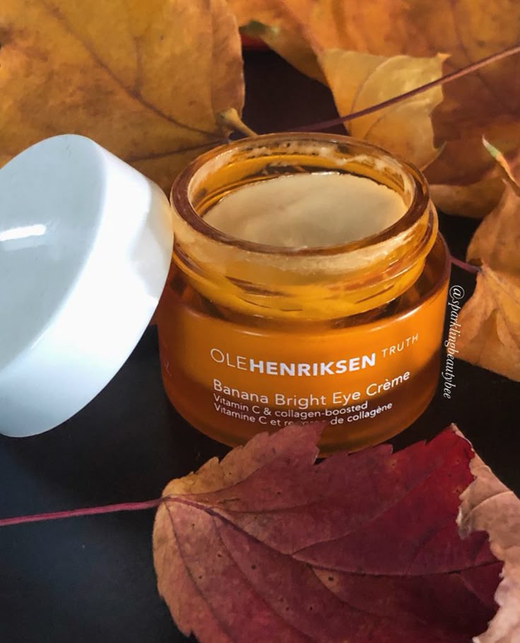 Ole Henriksen Banana Bright Eye Crème jar surrounded by autumn leaves, highlighting vibrant skincare.