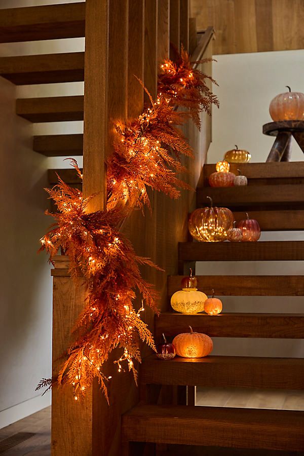 Rustic staircase with glowing autumn garland and lit pumpkins, creating a cozy, festive ambiance. Perfect for fall home decor inspiration.