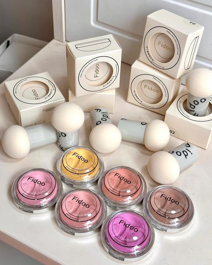 Cosmetic collection with blushes and sponges in elegant packaging, showcasing diverse shades for a vibrant beauty routine.
