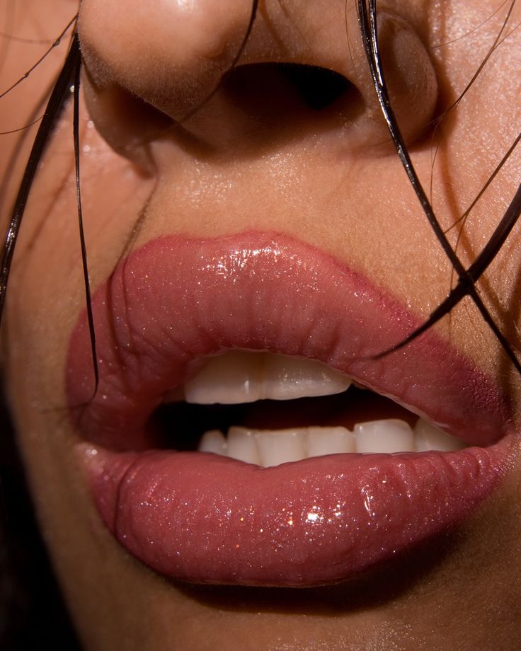 Close-up of glossy pink lips with wet hair strands, showcasing a sensual beauty and makeup style.