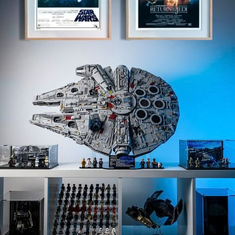 LEGO Millennium Falcon displayed on a shelf with Star Wars movie posters and collectibles in the background.