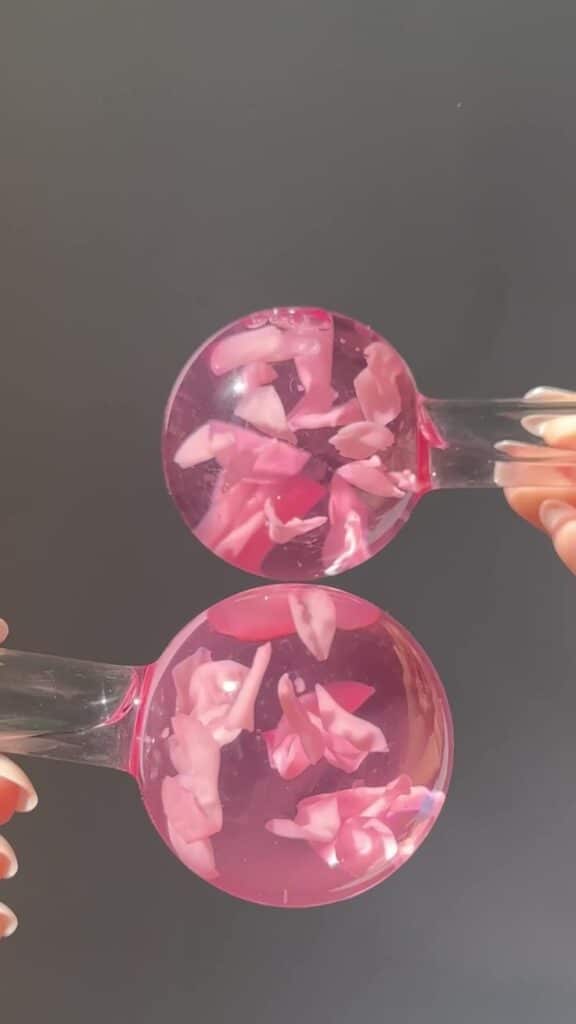 Pink floral liquid spheres with petal infusions against a gray background, enhancing a serene and elegant aesthetic.