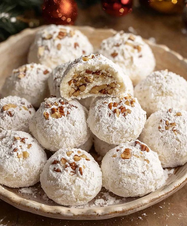 Plate of powdered sugar-coated snowball cookies with pecan pieces, perfect for holiday treats.