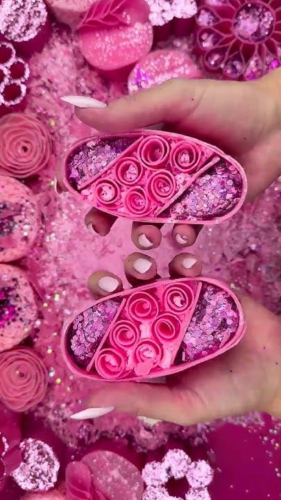 Hands holding a vibrant pink soap with spiral patterns and glitter, surrounded by a decorative pink background. Perfect for spa or beauty themes.