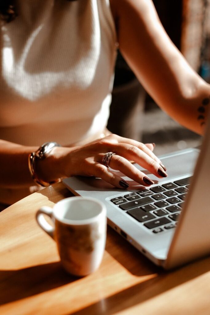 Person working on a laptop with coffee cup, showcasing productivity and focus in a warm-lit space.