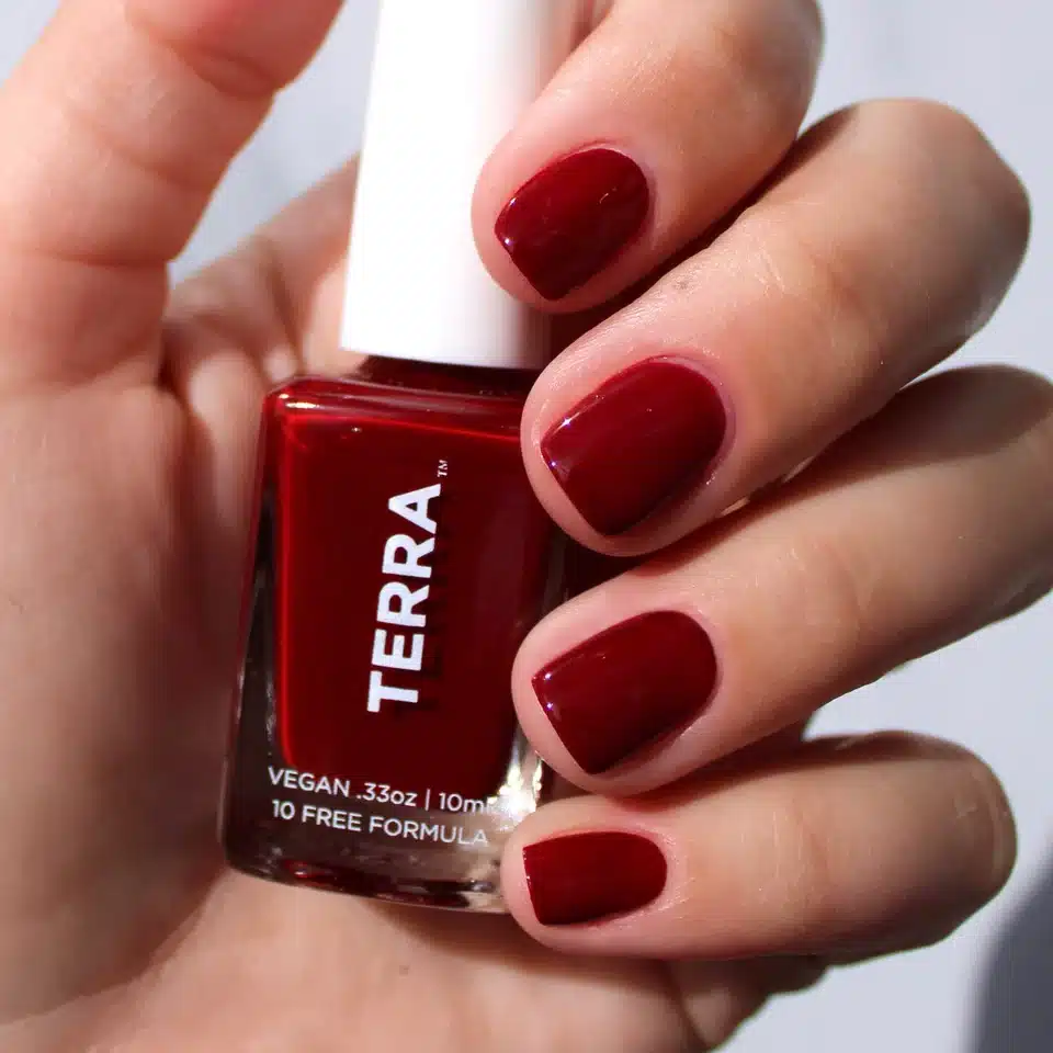 Red vegan nail polish on manicured nails, showcasing Terra brand's 10-free formula in a striking glossy finish.