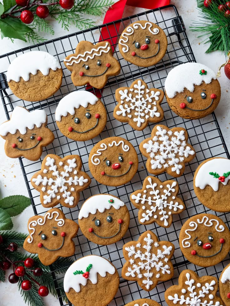 Festive gingerbread cookies with icing on a cooling rack, featuring snowflakes and smiling faces, perfect for Christmas celebrations.