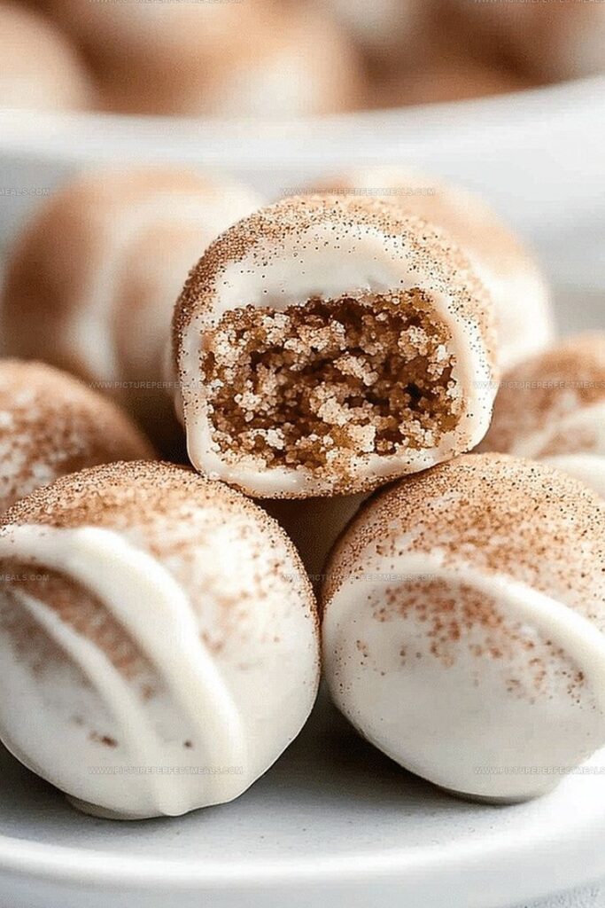 Close-up of cinnamon sugar-coated truffles with a white chocolate shell on a plate. Indulgent sweet treat perfect for desserts.