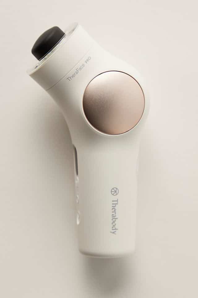 White Therabody Theraface Pro device on a white background, featuring a sleek design and gold accents.