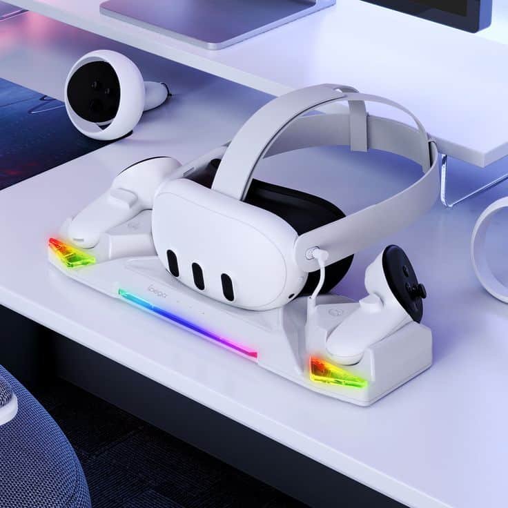 White VR headset and controllers on a sleek charging dock with colorful LED lights on a modern desk setup.