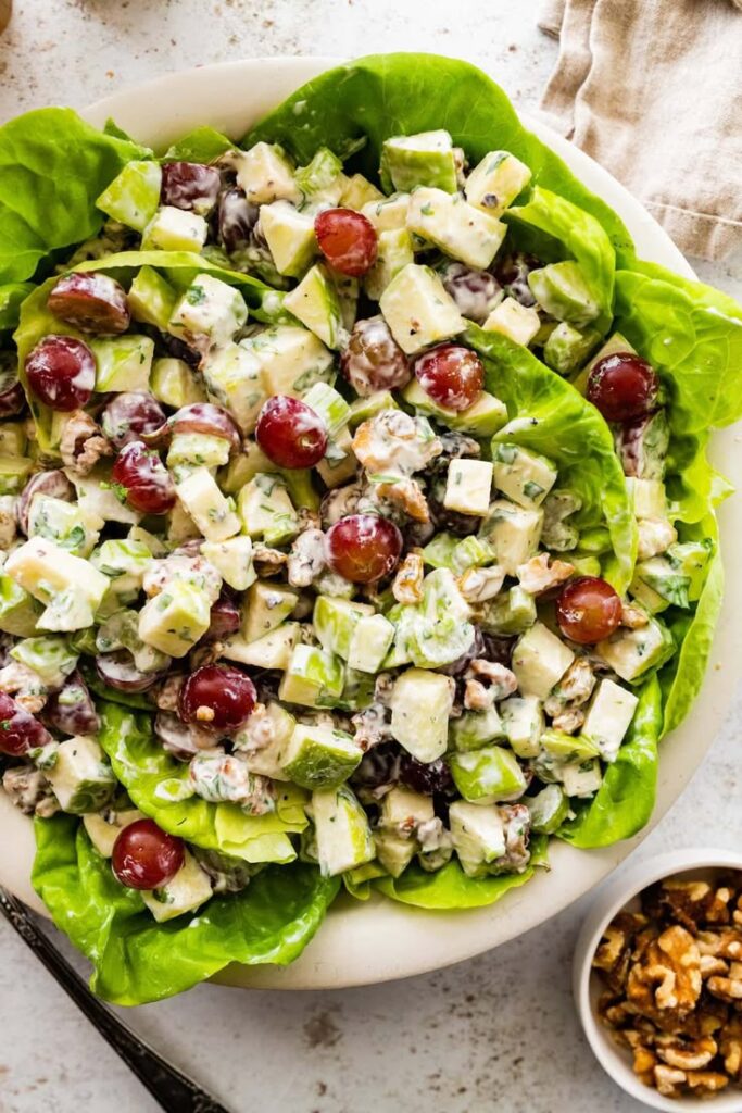 Fresh Waldorf salad with apples, grapes, celery, and walnuts on a bed of lettuce. Creamy dressing. Healthy and delicious!