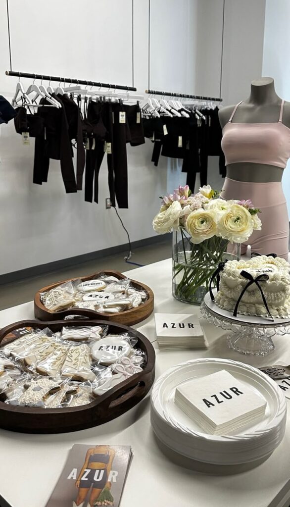 Chic showroom display with Azur activewear, elegant cookies, and floral decor on a table, perfect for stylish lifestyle inspiration.