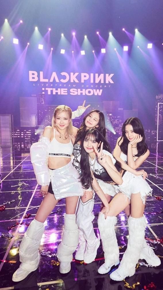 K-pop group posing on stage at a livestream concert titled The Show with dynamic lighting and vibrant outfits.