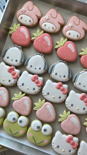Colorful, cute cookies shaped like animals and strawberries in a tray, decorated with pink, green, and white icing. Perfect for kids' parties!