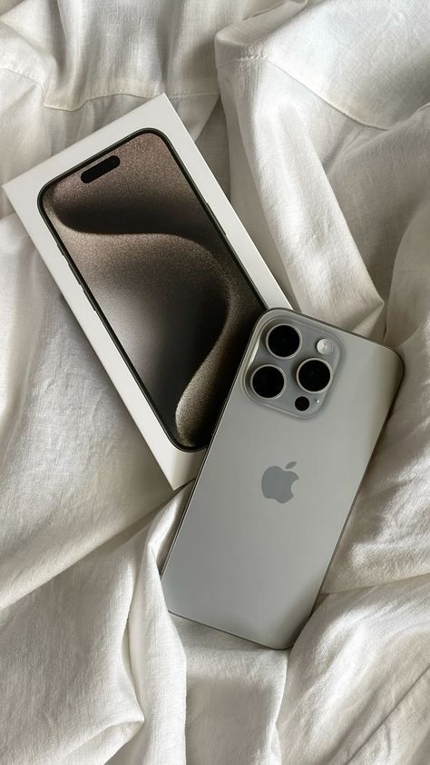 Sleek smartphone with triple camera and box on white fabric, showcasing modern design and technology.