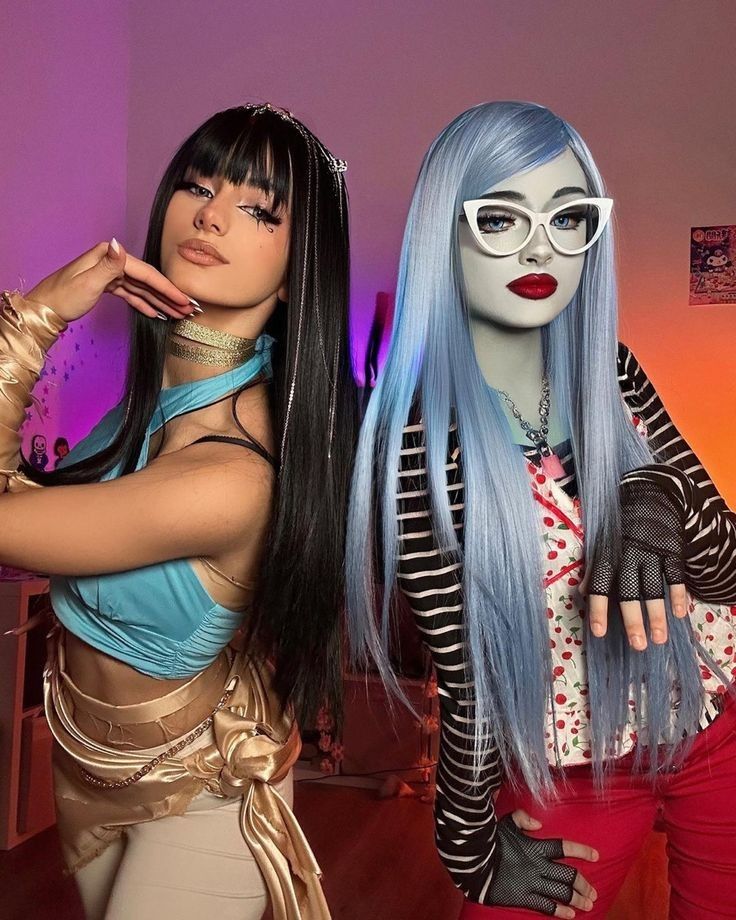 Two people in creative cosplay outfits, one in light blue and gold attire, the other in a striped top with blue wig and glasses.