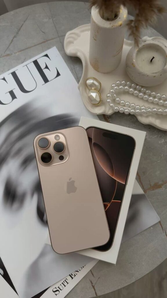 Gold smartphone on a magazine beside elegant jewelry and decor, blending tech with style in a chic setting.