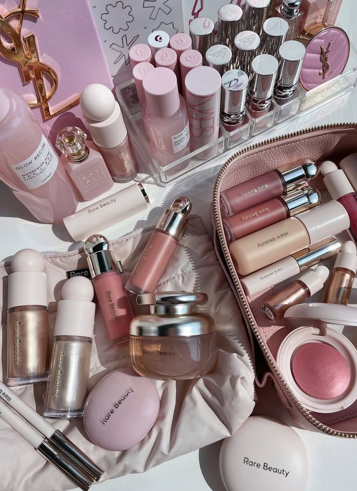 Assorted pink makeup products neatly arranged, including lipsticks, creams, and a cosmetic bag. Beauty and skincare essentials.