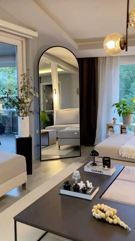 Modern living room with elegant decor, soft couches, large mirror, and stylish accessories in neutral tones.