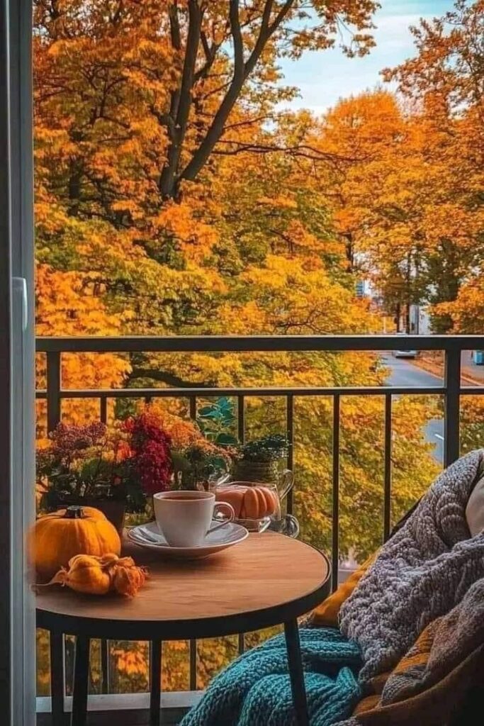 Cozy balcony with autumn view, coffee, pumpkins, and knitted blankets for a perfect fall day relaxation.