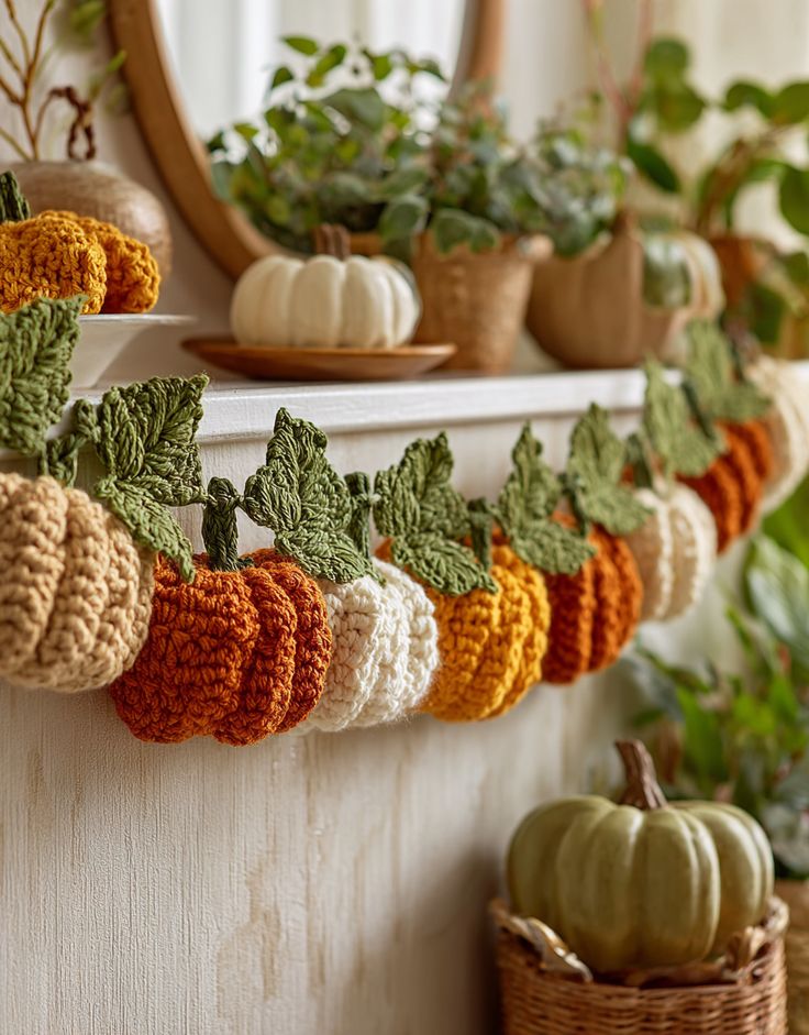 Crochet pumpkin garland decorating a cozy mantel with plants and autumn accents. Perfect fall home decoration idea.
